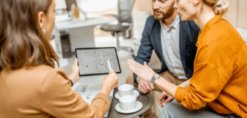 Young and lovely couple choosing a new house to buy, looking on the projects with a sales manager in the office of real estate agency